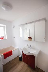 吕贝克Wohnen am Park的白色的浴室设有水槽和红色毛巾