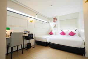 曼谷Rose Apple Hotel的酒店客房配有两张床、一张书桌和一张书桌。