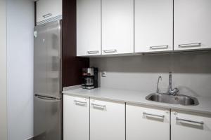 托里代巴拉AT157 Nova Torredembarra II的厨房配有白色橱柜和不锈钢冰箱