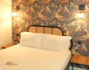 比亚里茨埃杜阿尔德七世酒店的一间卧室配有一张带花卉壁纸的床