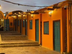 阿斯旺Fenti Nubian Resort的一座橙色的建筑,设有绿色的门和楼梯