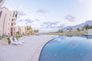 希法Le Sifah - Golf Lake Apartments的一座带两把椅子的度假村游泳池以及一座建筑