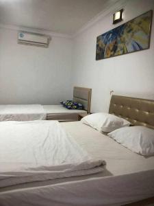 西哈努克Sea Inn Guesthouse Sihanoukville的一间卧室设有两张床,墙上挂着一幅画