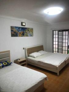 西哈努克Sea Inn Guesthouse Sihanoukville的一间卧室设有两张床,墙上挂着一幅画