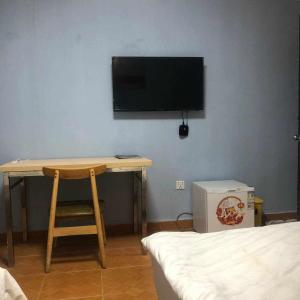 西哈努克Sea Inn Guesthouse Sihanoukville的一间房间,配有一张桌子和一台墙上的电视