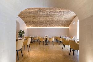 锡拉库扎Palazzo Artemide - VRetreats的一间设有桌椅的用餐室和砖砌天花板