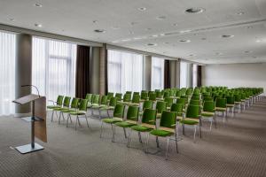 海德堡IntercityHotel Heidelberg的一间会议室,配有绿色椅子和讲台