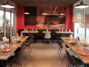 塞维利亚宜必思塞维利亚酒店的餐厅设有木桌和椅子,拥有红色的墙壁
