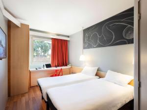 塞维利亚宜必思塞维利亚酒店的配有窗户的酒店客房内的两张床