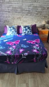 托莱多Chalet con piscina en escalona的一张带粉红色蝴蝶的蓝色棉被的床