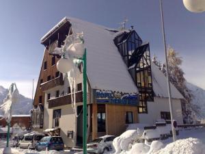 莱德萨阿尔卑斯HOTEL DES NEIGES的一座被雪覆盖的建筑,前面有汽车停放