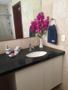 泰巴Taiba Beach Resort Casa com piscina的浴室水槽上放着一瓶粉红色的花