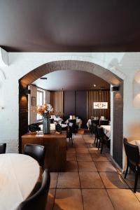 托尔豪特Hotel Brasserie De Beiaard的一个带桌椅的餐厅和一个大型拱门