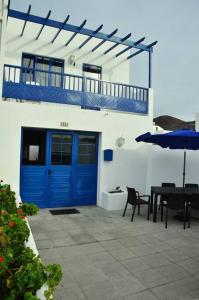 埃尔戈尔福Casa Leyna的一个带蓝色门、桌子和遮阳伞的庭院
