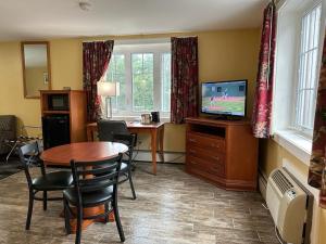 北康威瑞士小屋村旅馆的客厅配有桌子和电视