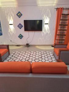 克里比Chez Roland的客厅配有橙色沙发和平面电视。