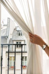 巴黎Snob Hotel的女人打开窗户的窗帘