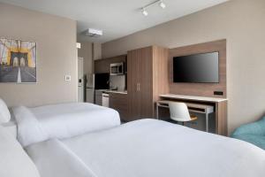 布鲁克林TownePlace Suites by Marriott New York Brooklyn的酒店客房设有两张床、一张书桌和电视