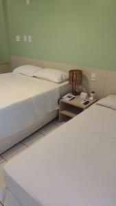 巴雷里尼亚斯Gran Lençóis Flat的一间卧室配有两张床,还有一个床头柜和一张桌子