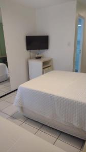 巴雷里尼亚斯Gran Lençóis Flat的卧室配有白色的床和平面电视。