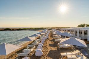 斯培基奥拉Infinito Resort的海滩上的一排遮阳伞和椅子