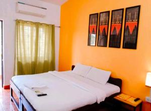 巴加Baga Sea Link的一间卧室配有一张白色的床和橙色的墙壁