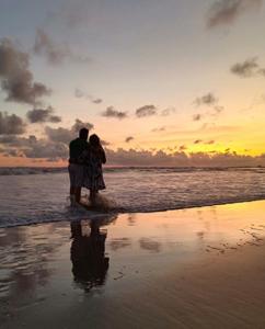 巴加Baga Sea Link的一对夫妇站在海滩上欣赏日落