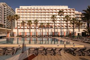 圣保罗湾城QAWRA Palace Resort & SPA的一座建筑前的带椅子和游泳池的酒店