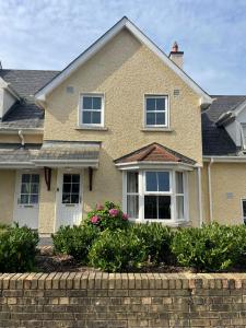 沃特福德Faithlegg Estate, Mews Holiday Home, Waterford的砖墙和灌木的房子