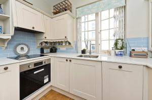 伦敦Veeve - Mews & Blues的厨房配有白色橱柜、水槽和窗户。