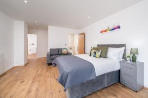 伦敦Skyvillion - London River Thames Top Floor Apartments by Woolwich Ferry, Mins to London ExCel, O2 Arena , London City Airport with Parking的一间卧室配有一张大床和一把椅子