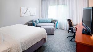 罗阿诺Courtyard by Marriott Roanoke Airport的配有一张床和一把椅子的酒店客房