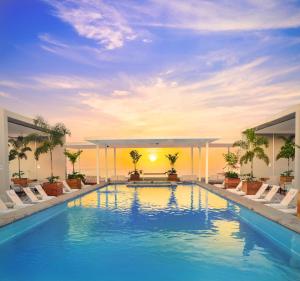 巴亚尔塔港Hotel Mio Vallarta Unique & Different- Adults Only的一个带椅子的游泳池,享有日落美景