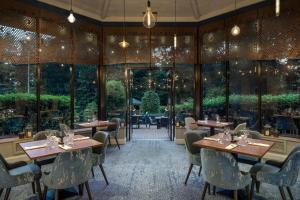 史云顿Delta Hotels by Marriott Swindon的餐厅设有桌椅和大窗户。