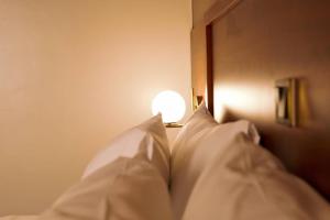 恩德培Blueberries Hotel的一张带白色枕头的床和灯