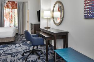 盖恩斯维尔Fairfield Inn & Suites by Marriott Gainesville的酒店客房配有书桌和蓝椅