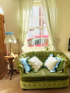 埃文河畔斯特拉特福Traditional 2 bedroom Cottage的窗户前的绿色沙发,上面有枕头