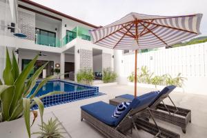 象岛Koh Chang Luxury Pool Villas的一个带椅子和遮阳伞的庭院和一个游泳池