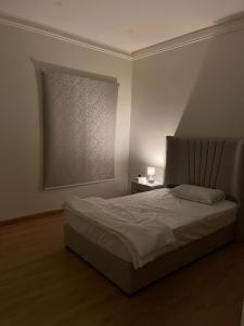 阿可贺巴Family Furnished Apartment in Khobar的一间卧室配有一张床和一扇带灯的窗户