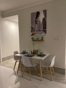 阿可贺巴Family Furnished Apartment in Khobar的一间配备有白色桌椅的用餐室