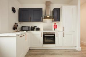 诺里奇Pottergate Views的厨房配有白色橱柜、水槽和炉灶。