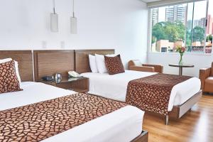 麦德林Hotel Poblado Alejandria的酒店客房设有两张床和窗户。