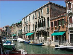 威尼斯奥多尼公寓式酒店的一群船在运河上,在建筑物旁边