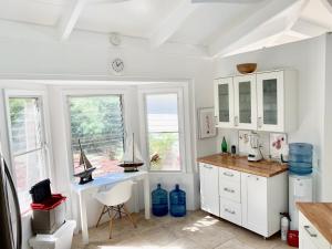 Teagues BayHidden Valley Villa的白色的厨房配有书桌和窗户