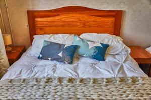 奥克泰港Hostal Triwe的一张带白色床单和蓝色枕头的床