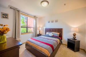 基洛纳Resort Style Living with Private Lawn and Patio的一间卧室配有一张床、一张书桌和一个窗户。