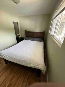 伯纳比Cozy Capitol Hill Bungalow - 3BD/2BA Retreat的一间卧室配有一张带白色床单的床和一扇窗户。