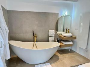 芒德Domaine de Mende Brenoux Suites & SPA的一个带镜子的浴室内的白色大浴缸