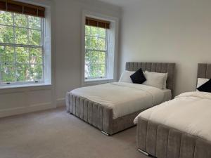 伦敦Kensington Luxury Apartments的一间卧室设有两张床和两个窗户。