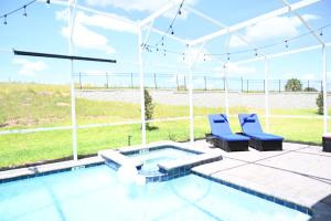 基西米Luxurious 8-Room Oasis near Disney的一个带两把蓝色椅子的庭院和一个游泳池
